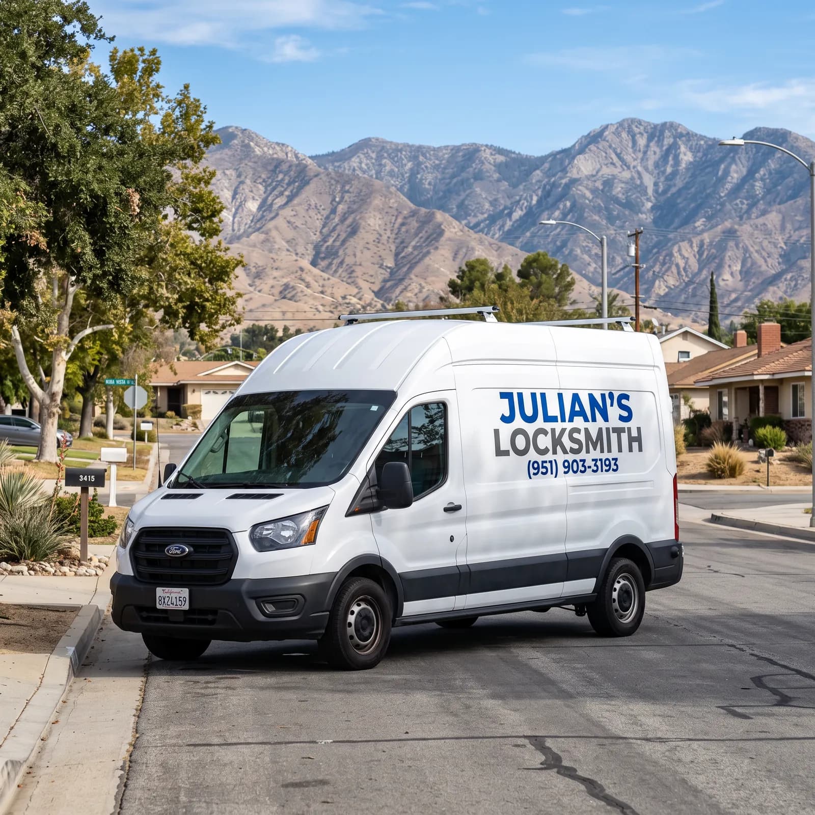 White Julian's Locksmith service van with the phone number (951) 903-3193 on its side, parked on a San Bernardino street below the mountains
